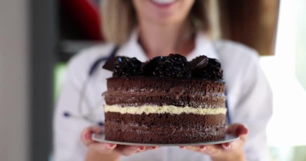 Nutricionista tiene pastel de chocolate en las manos. Daño y beneficios del azúcar y los dulces para el cuerpo - Metraje, vídeo
