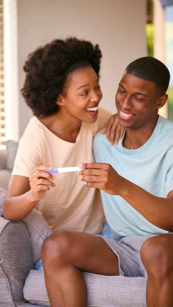 Возбужденная пара в спальне дома празднует положительный результат теста на беременность - Фото, изображение