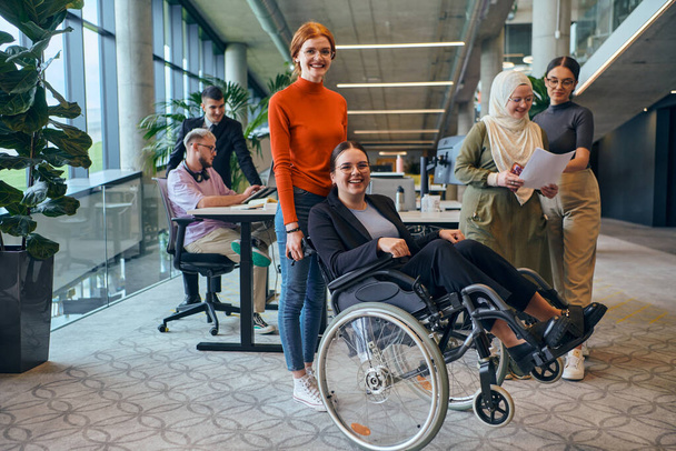 A diverse group of business colleagues is having fun with their wheelchair-using colleague, demonstrating their attention and inclusivity in the workplace.  - Foto, Imagem