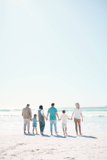 Duża rodzina, plaża i letnie wakacje na makiecie w podróży, wakacje na świeżym powietrzu lub razem w słoneczny dzień. Widok z tyłu rodziców, dziadków lub dzieci na wybrzeżu oceanu w zabawy bonding lub przerwy na morzu w przyrodzie. - Zdjęcie, obraz