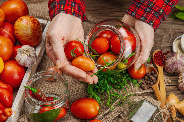 季節の野菜コンセプトを保存しました. トマト,チリ,グリーン,オニオン,ニンニクの収穫. 女性の手は缶詰食品,調理プロセスのための成分を準備します. 健康的なレシピ,家庭料理,トップビュー - 写真・画像