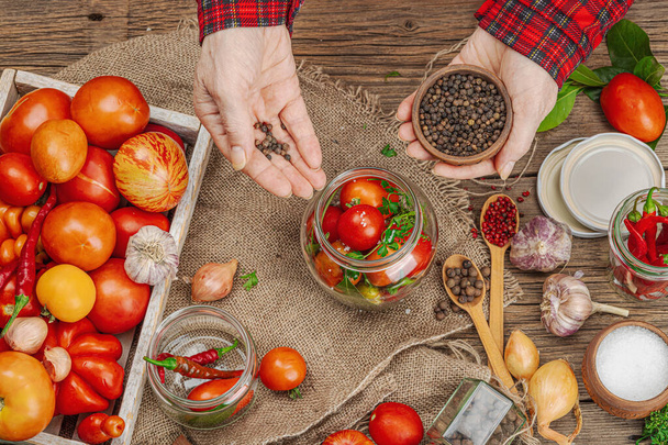 Preserved season vegetable concept. Harvest of tomato, chili, greens, onion and garlic. Woman's hands prepare ingredients for canned food, cooking process. Healthy recipes, home cuisine, top view - Photo, Image