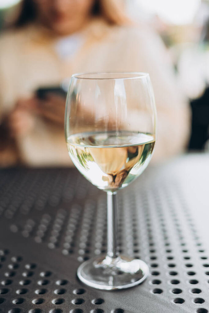 Glas mit Weißwein auf dem Tisch im Restaurant, Alkohol im Hintergrund - Foto, Bild