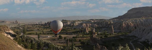 One hot air balloon over fairy chimneys and valley in Cappadocia, Turkey. Extreme touristic adventures and travel concept. - Photo, image