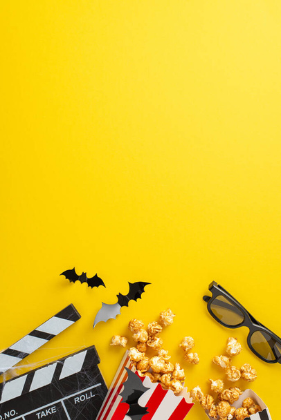 Freunde gönnen sich ein filmisches Treffen zu Halloween, das aus der vertikalen Sicht von oben aufgenommen wird. Popcornboxen, gruselige Dekorationen geben den Ton für einen unterhaltsamen Filmabend auf gelbem Hintergrund mit leerem Raum an - Foto, Bild