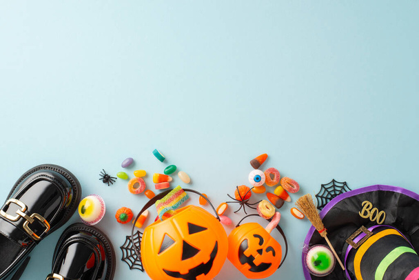 Lebendiges Konzept für die Kinder-Halloween-Nacht. Top-Down-Foto enthüllt Leckereien, Hexenkostüm Attribute und unheimliche Dekor auf isoliertem blauen Hintergrund, ermöglicht das Einfügen von Werbung oder Textmaterial - Foto, Bild