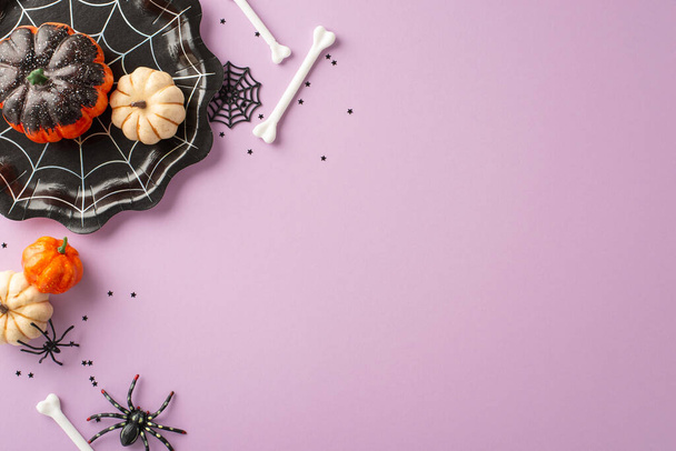 Verwandeln Sie Ihren Halloween-Tisch: Aufnahme von oben zeigt spinnennetzförmigen Teller, Kürbisse, Spinnen, Knochen und Konfetti auf fliederfarbenem Hintergrund. Viel Platz für Text oder Werbung - Foto, Bild