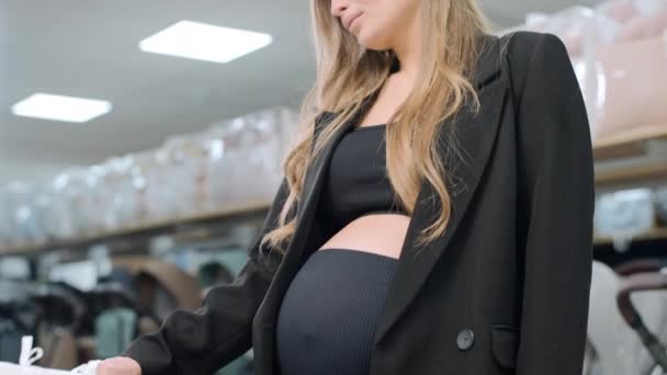 Mujer embarazada eligiendo la cama de bebé en la tienda. Preparándose para convertirse en madre - Imágenes, Vídeo