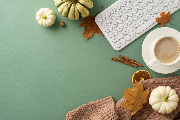Fall-themed workspace idea. Top view of keyboard, cozy sweater, steaming cup of coffee, pattypans, acorn, cinnamon sticks, maple leaves, dried orange slice on green backdrop. Space for text or ads - Photo, Image