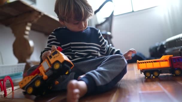 Nuori poika harjoittaa kuorma-auton leluja - lyömällä auton autoja keskittyneessä pelata kotona, valkoihoinen lapsi upotettu pelata - pieni poika yhteentörmäys kuorma-auton leluja yhdessä kotona - Materiaali, video