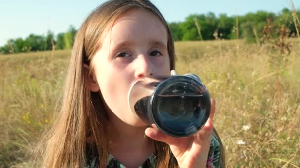 Dívka pitná voda ze skleněné láhve v přírodě. - Záběry, video