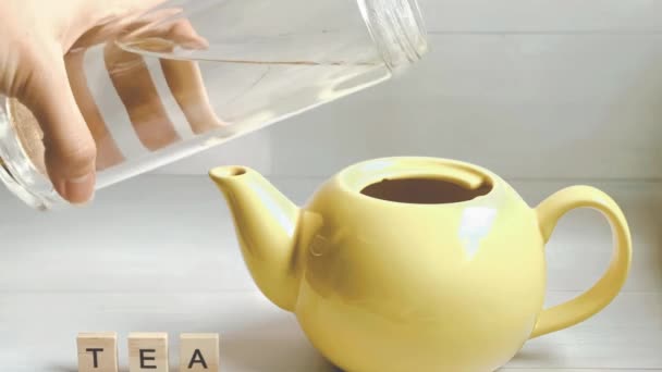 Stop-motion animation of tea preparation: water, lemon, tea bag added to the kettle and the sign tea neer the kettle. - Footage, Video