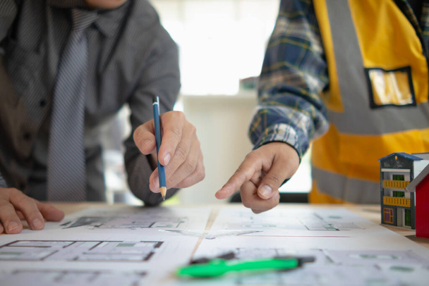 Inżynierowie budowlani dyskutują i wymieniają się pomysłami z architektami, aby poprawić plany domów w celu zaspokojenia potrzeb klientów. Koncepcja wymiany pomysłów projektowych między inżynierami budowlanymi a architektami. - Zdjęcie, obraz