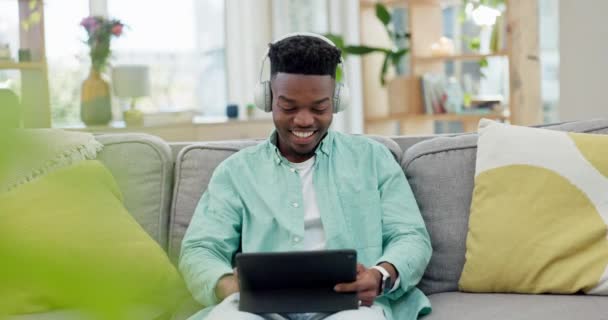 Casa, fones de ouvido e homem preto com tablet, streaming de música e rádio com conexão, relaxar e som. Africano pessoa, fone de ouvido e cara em um sofá, tecnologia e ouvir áudio com aplicativo digital. - Filmagem, Vídeo