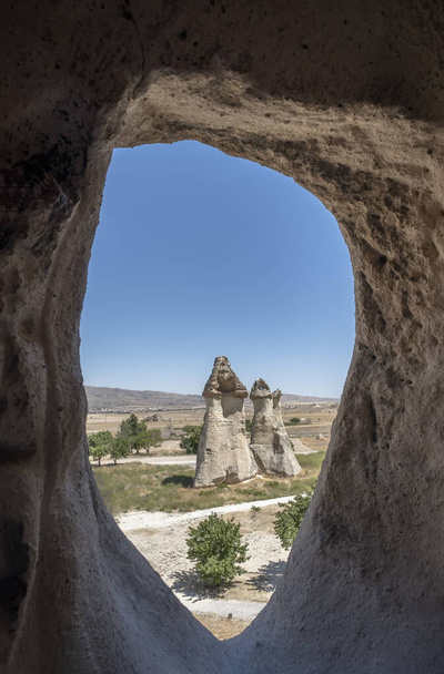 τυπική θέα νεράιδα καμινάδα μέσα από ένα σκαμμένο σπήλαιο, γεωλογικός σχηματισμός του διαβρωμένου βράχου, στο υπαίθριο μουσείο του Goreme, στην Καππαδοκία, Τουρκία, κάθετη - Φωτογραφία, εικόνα