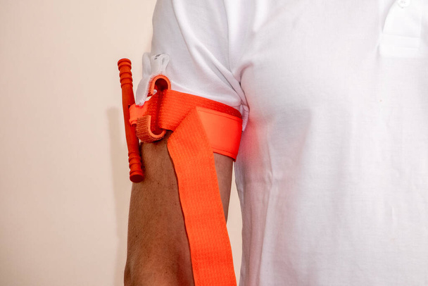 Ein Mitarbeiter des Gesundheitswesens demonstriert, wie man ein Tourniquet auf den Arm aufträgt, um Blutungen bei Verletzungen oder Unfällen zu stoppen - Foto, Bild