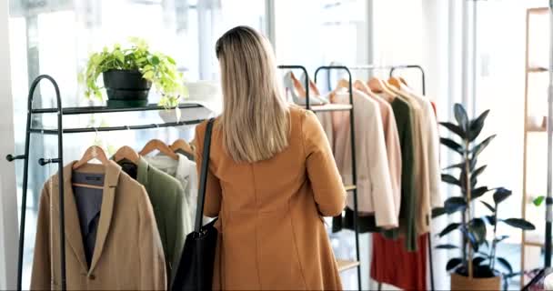 Woman, customer and fashion with clothing rack in shopping, sale or discount at boutique store. Female person or shopper checking line of clothes in fabric, material or retail shop at the indoor mall. - Footage, Video