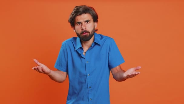 What Why. Sincere irritated man raising hands in indignant expression, ask reason of failure demonstrating disbelief irritation by trouble. Handsome confused middle eastern guy on orange background - Footage, Video