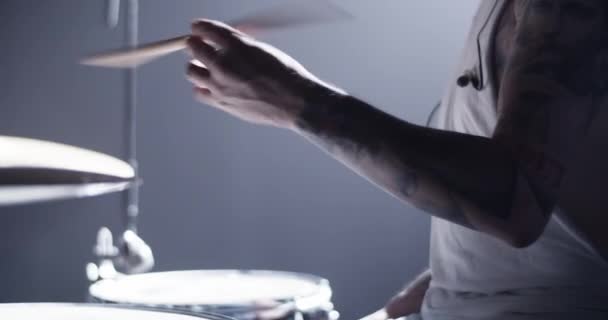Vista lateral da colheita baterista masculino anônimo com tatuagens fazendo truques enquanto gira batom na mão enquanto executa no palco escuro - Filmagem, Vídeo
