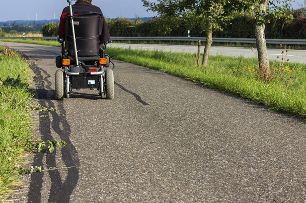 ドイツの夏の道路の横にモーターが付いている車輪の椅子 - 写真・画像
