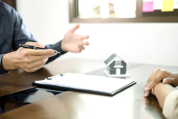 Un agente de bienes raíces con un modelo de casa está hablando con los clientes sobre la compra de un seguro de vivienda. Concepto de seguro doméstico. - Foto, imagen