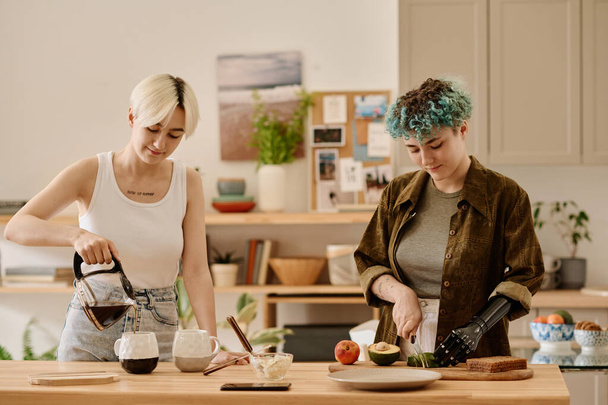 Λεσβιακό ζευγάρι ετοιμάζει πρωινό και φτιάχνει καφέ μαζί στην κουζίνα - Φωτογραφία, εικόνα