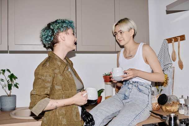 Joven pareja lesbiana disfrutando de una taza de café mientras están sentados en la cocina - Foto, imagen