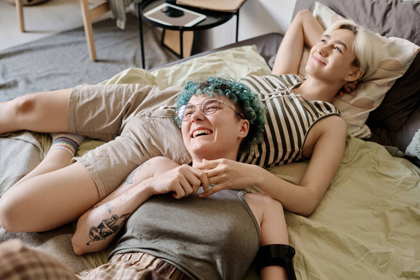 Glückliche lesbische Mädchen entspannen sich auf dem Bett im Schlafzimmer und genießen einander - Foto, Bild