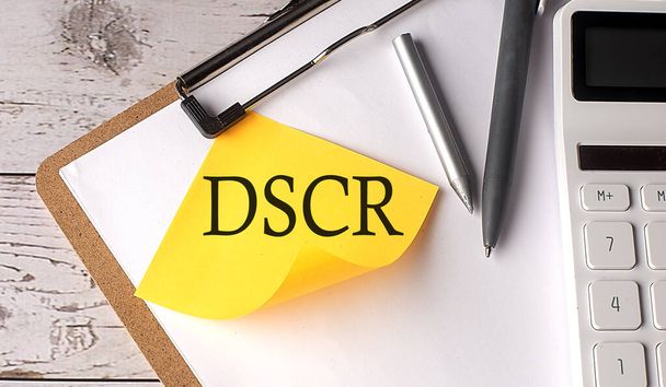 Parola DSCR su adesivo giallo con calcolatrice, penna e appunti - Foto, immagini