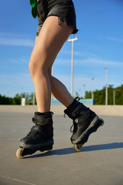 Κοντινό πλάνο θηλυκά πόδια φορώντας πατίνια πάνω από την άσφαλτο rollerdrom φόντο. Θερινός χρόνος αναψυχής - Φωτογραφία, εικόνα