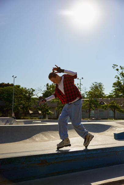 Teenager rollerskater balancing on pedestal performing extremely ride tricks. Recreation activity at skating park - Photo, Image