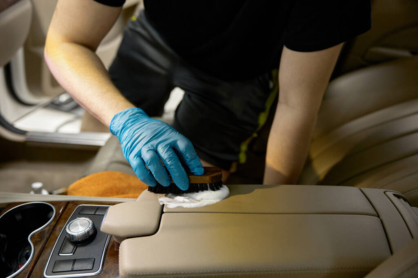 Processus de nettoyage et de lavage sélectif des pièces intérieures en cuir automobile avec des cosmétiques de nettoyage professionnels et des outils souples - Photo, image