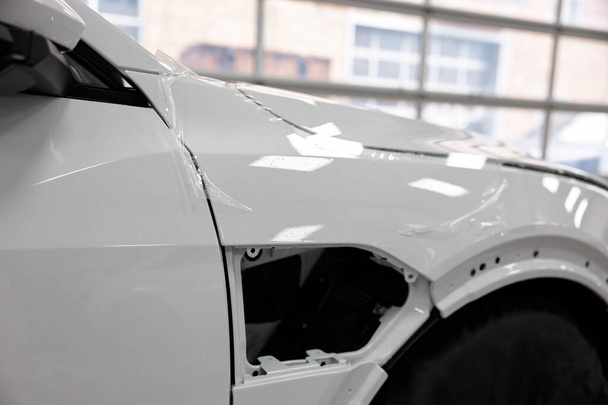Folia na świeżo pomalowanym nadwoziu samochodu dla ochrony przed uszkodzeniami. Działalność w zakresie opieki nad pojazdami - Zdjęcie, obraz