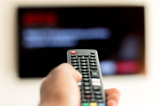 Adult operating remote of a smart TV - Photo, Image