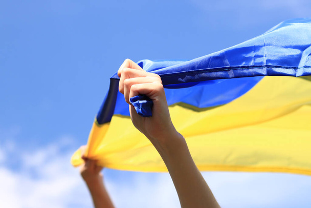 Uma rapariga com uma bandeira amarelo-azul nas mãos. A bandeira treme ao vento. Patriotismo. Bandeira amarela e azul da Ucrânia nas mãos da mulher - Foto, Imagem