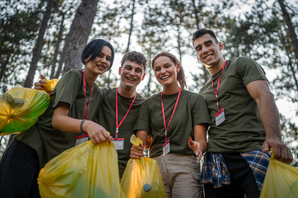 portret van groep vrienden vrijwilligers voor te bereiden om afval en schoon bos natuur verzamelen in de zomer dag slow motion - Foto, afbeelding