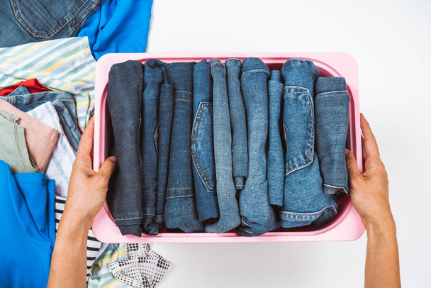 Woman hands tidying up clothes in basket at home. Vertical storage of clothing, tidying up, room cleaning, donation, recycling concept. - Photo, Image