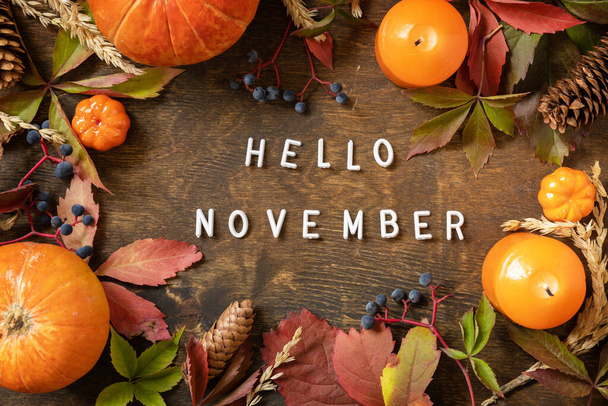 Merhaba Kasım metni, sonbahar sezonu. Tebrik kartı, dökülen yapraklar, tahta bir tahtanın üzerindeki balkabakları ve koniler. Sonbahar doğal arka planı. Yukarıdan görüntüle - Fotoğraf, Görsel