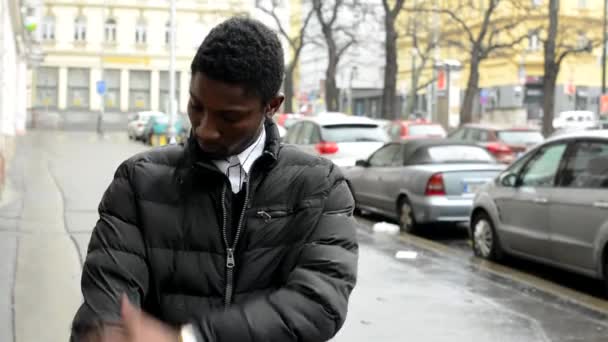 Fiatal, jóképű, fekete férfi helyesbíti, ruházati és mosoly - városi utcai autó - város - Felvétel, videó