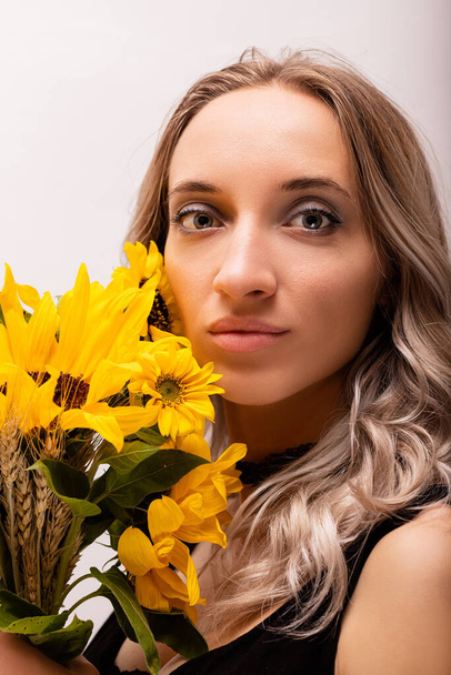 Heureuse femme joyeuse avec un bouquet de fleurs jaunes. Bouquet de tournesols. Photo de haute qualité - Photo, image