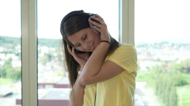 Jonge aantrekkelijke vrouw met koptelefoon die thuis muziek luistert en danst. Hoge kwaliteit 4k beeldmateriaal - Video