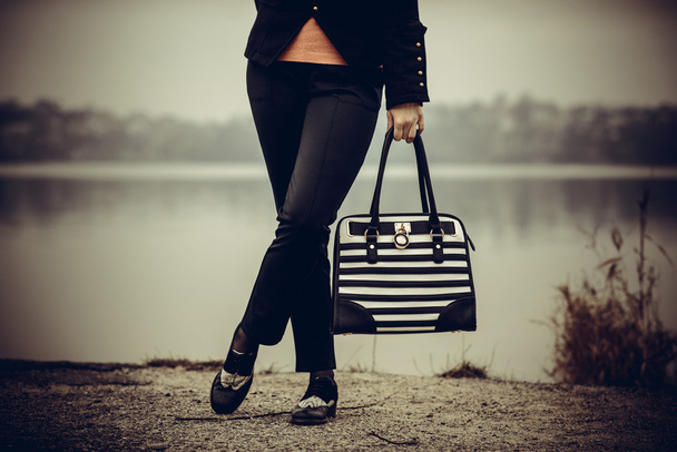 Tyttö musta ja valkoinen laukku käsissä
 - Valokuva, kuva