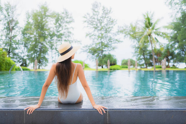 Retrato hermosa joven mujer asiática relajarse sonrisa ocio alrededor de la piscina al aire libre en el complejo hotelero casi playa de mar - Foto, Imagen