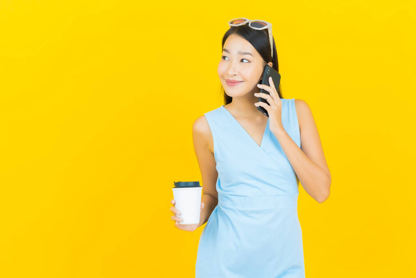 Retrato bonito jovem asiático mulher sorriso com telefone celular inteligente na cor amarela fundo - Foto, Imagem