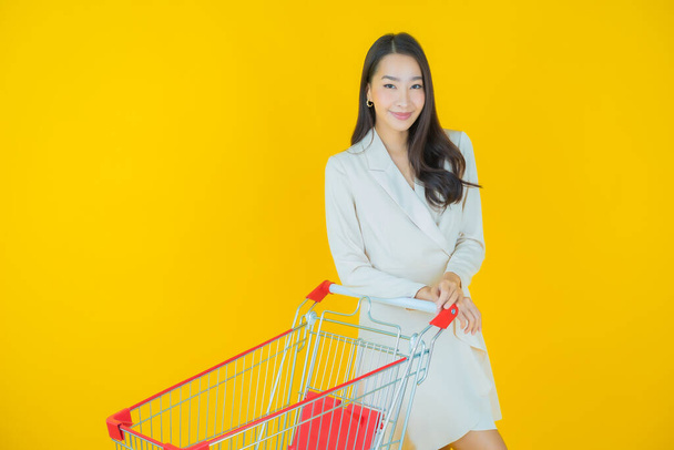 Retrato hermosa joven asiática mujer sonrisa con cesta de supermercado en color de fondo - Foto, Imagen
