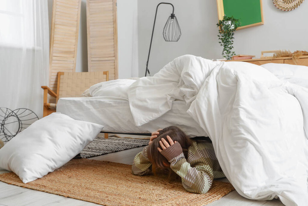 Vrouw verstopt zich voor aardbeving onder bed - Foto, afbeelding