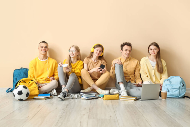Ομάδα μαθητών που κάθονται στο πάτωμα κοντά στον κίτρινο τοίχο - Φωτογραφία, εικόνα