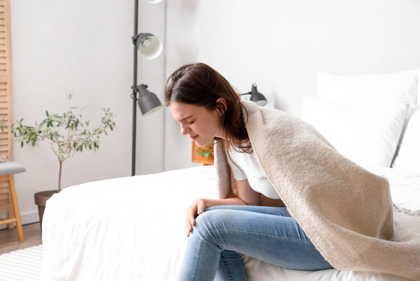 Young woman having menstrual cramps in bedroom - 写真・画像