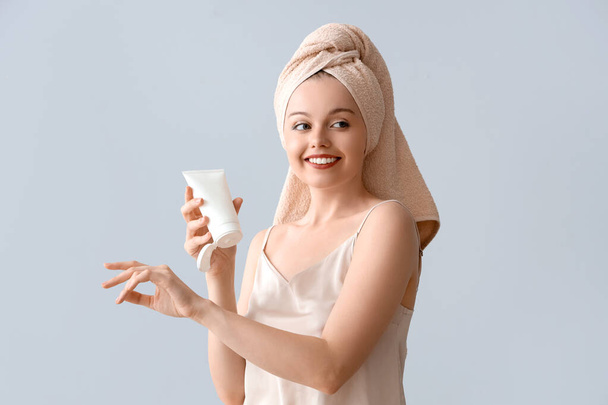 Csinos fiatal nő után zuhany alkalmazása krém ellen fény háttér - Fotó, kép