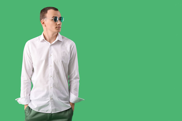 Hombre joven en gafas de sol sobre fondo verde - Foto, Imagen